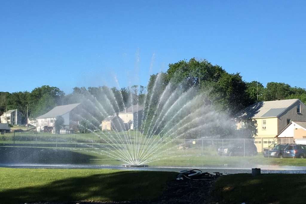 Otterbine Aries fountain in a community pond with houses in the background