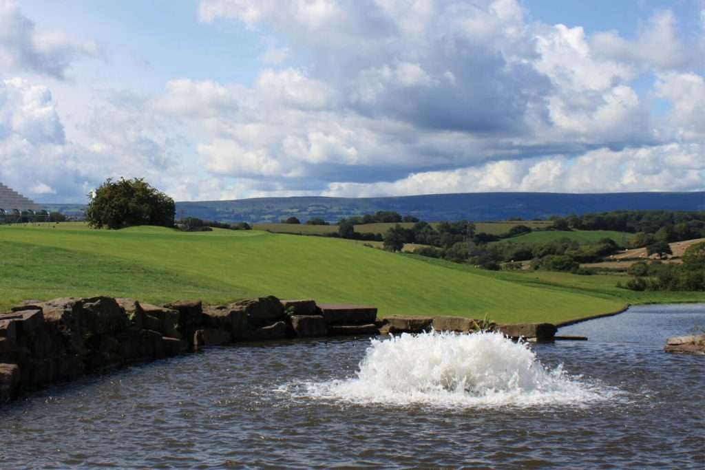 Otterbine High Volume fountain operating in a countryside pond with hills in the background