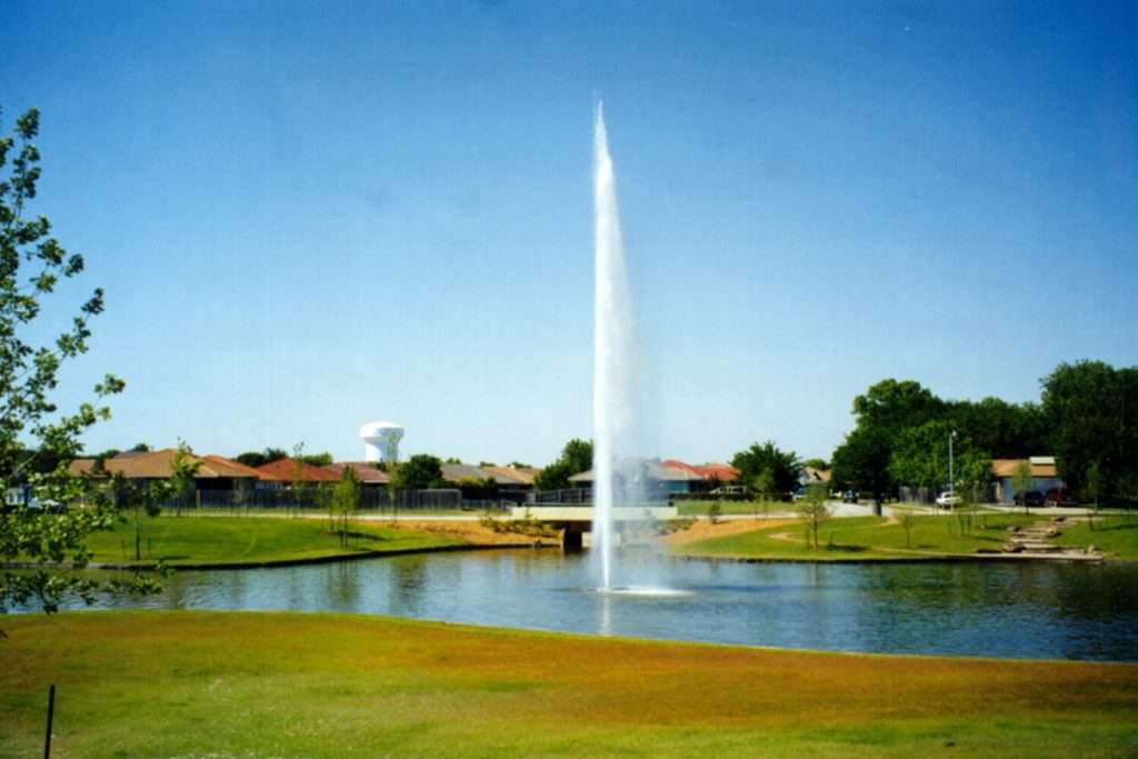Otterbine Mystic fountain with a tall vertical spray in a community lake surrounded by homes