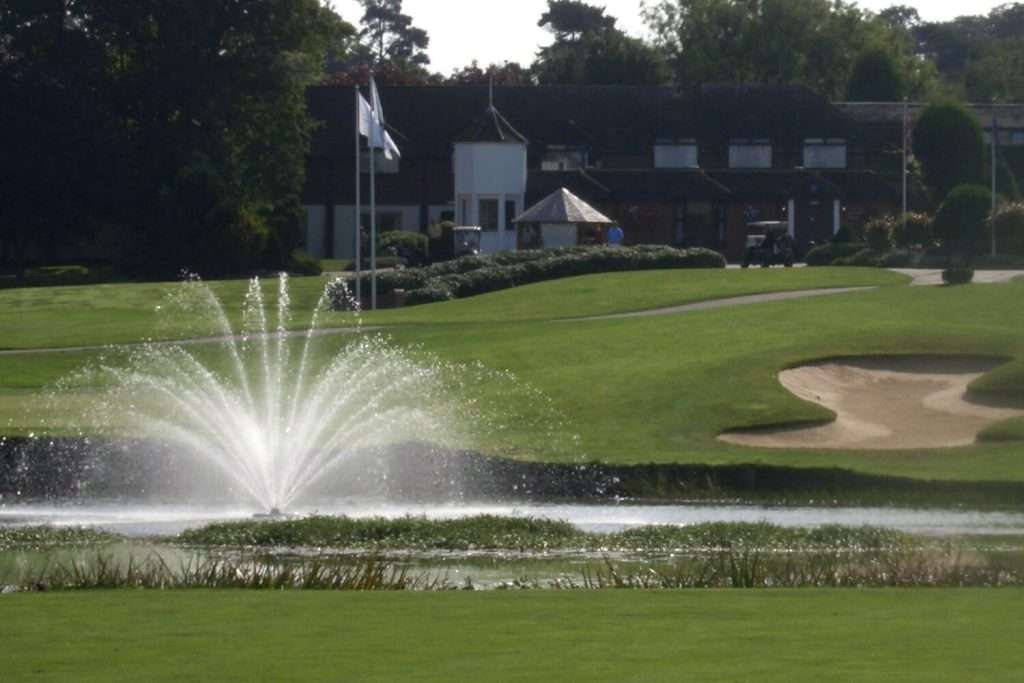 Golf course with water fountain and sand trap.