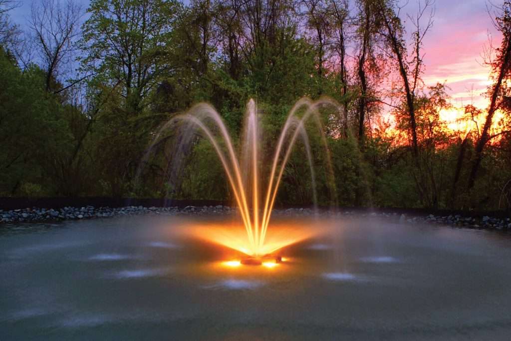 LED low voltage fountain glowing orange at sunset with water jets