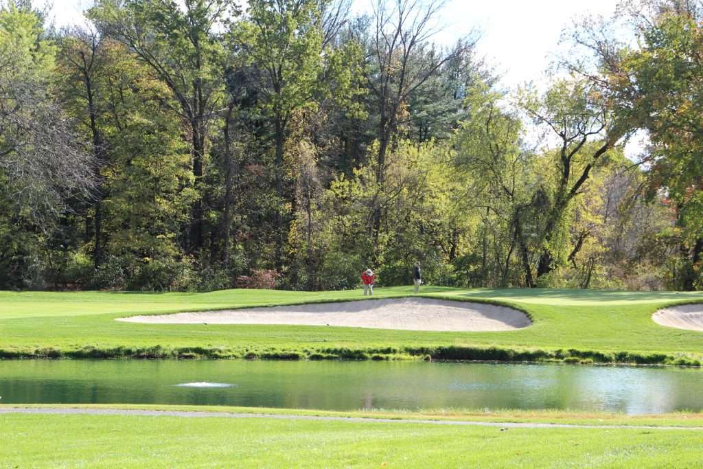 Golf course with sand trap and lush trees.
