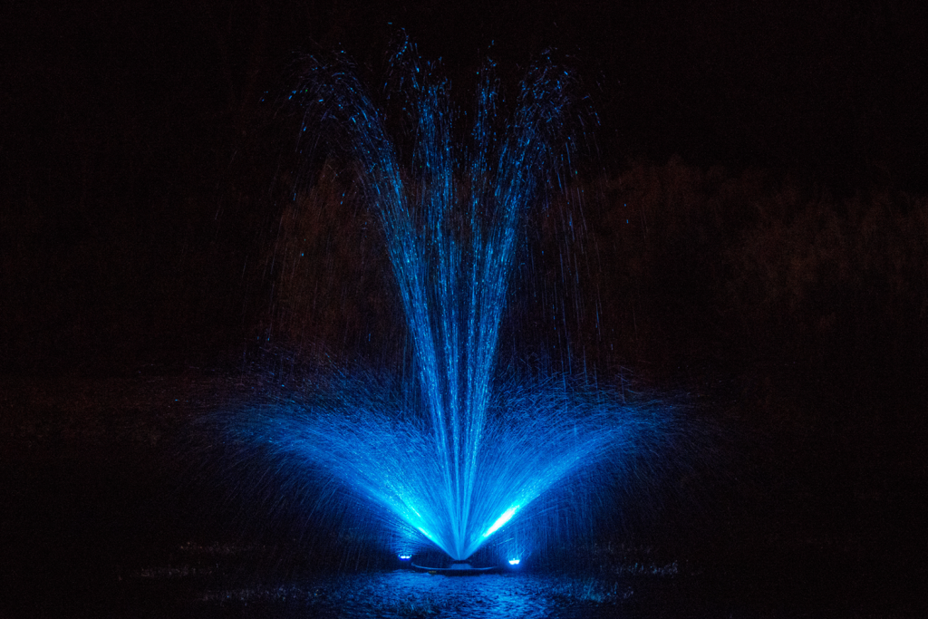 Otterbine Mini-RGBW fountain illuminated with vibrant blue lighting at night