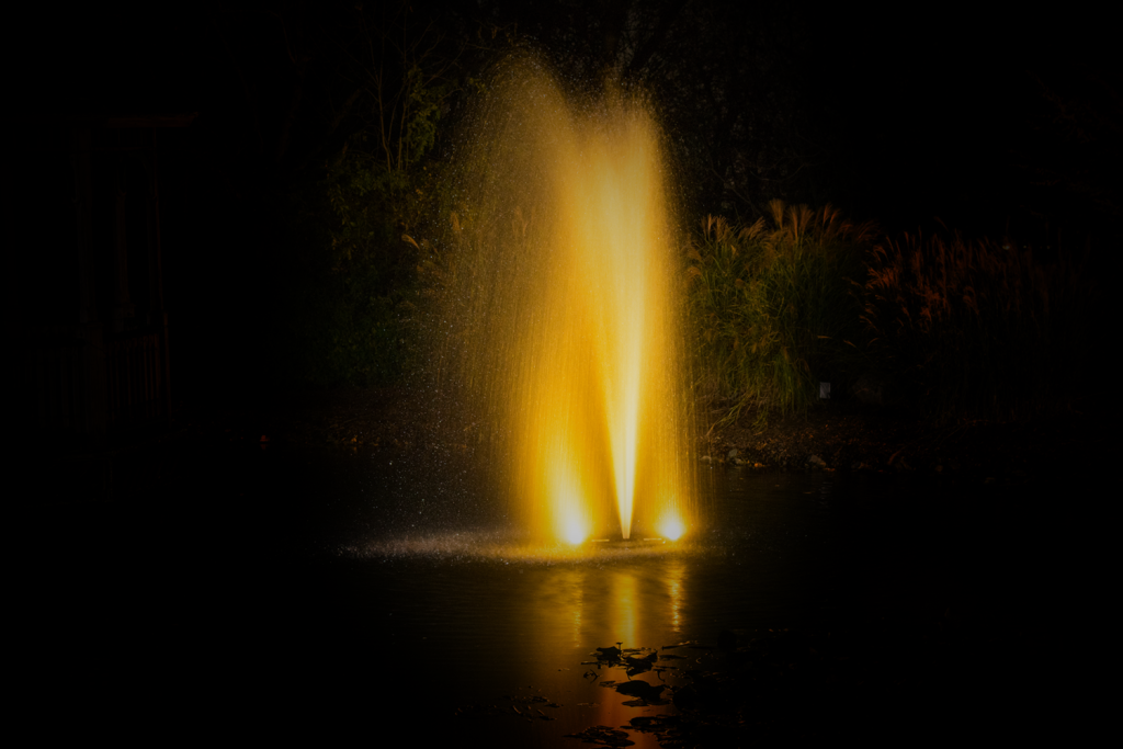 Otterbine Mini-RGBW fountain radiating golden yellow light with water reflections
