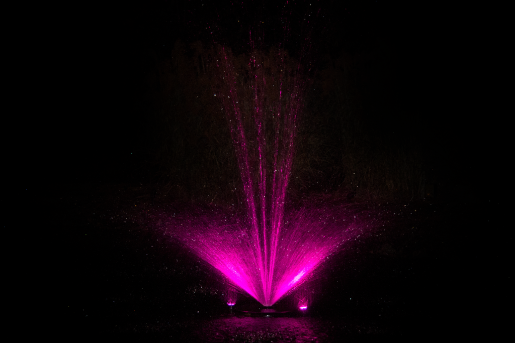 Otterbine Mini-RGBW fountain glowing with bright pink lights against dark background