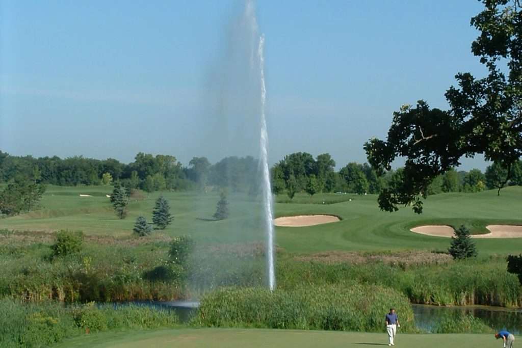 Golf course with large fountain and golfer in foreground.