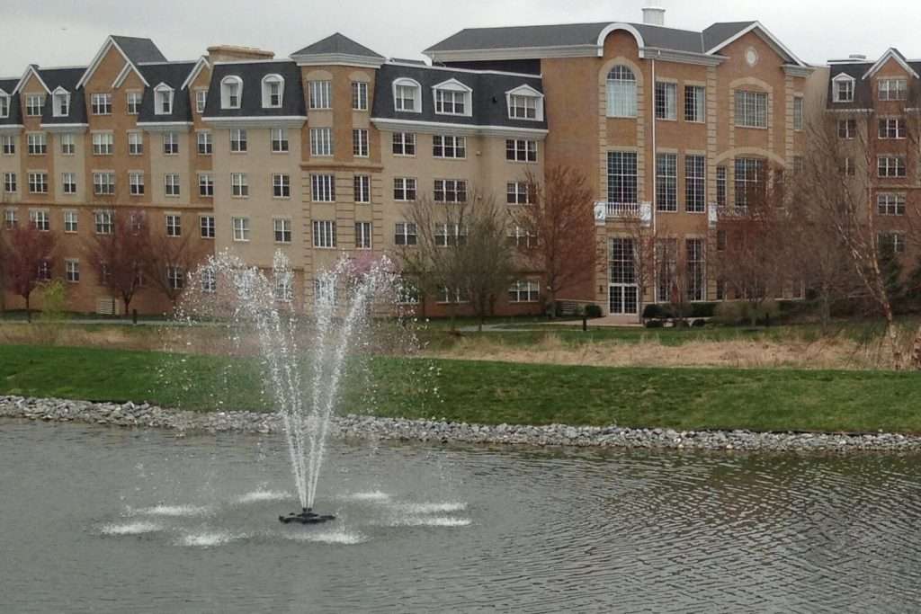 Fountain in front of large brick building with multiple windows.