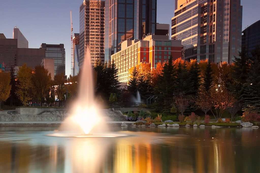 Otterbine Tristar fountain at dusk with city skyscrapers in the background