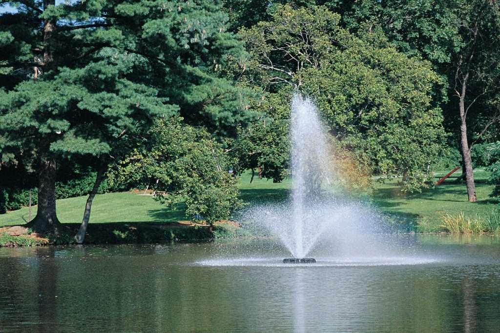 Fountain spraying water in a lush green park.